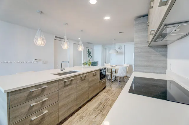 a view of a kitchen with kitchen island a stove a table and chairs in it