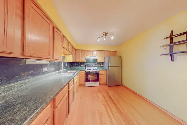 a kitchen with stainless steel appliances granite countertop a refrigerator a stove and a sink with granite countertops