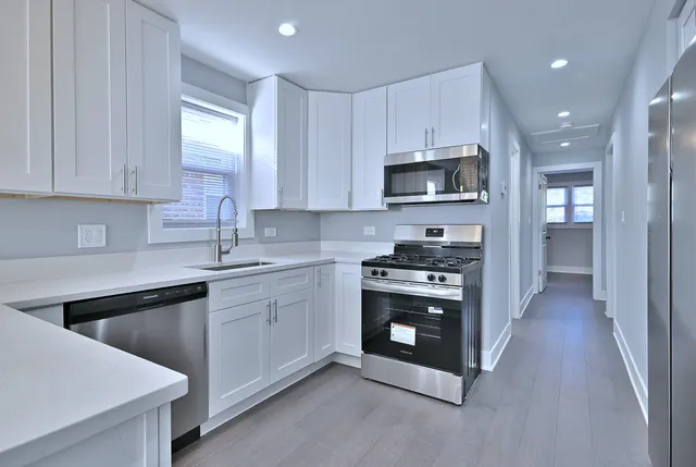 a kitchen with granite countertop a stove top oven a sink dishwasher and a refrigerator with wooden cabinets