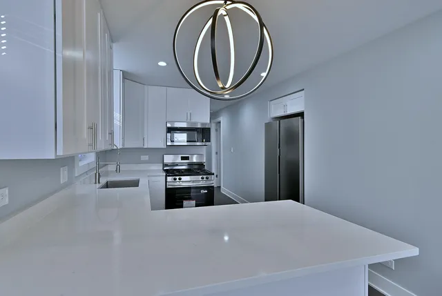 a kitchen with stainless steel appliances a stove top oven a sink and a refrigerator with wooden floor