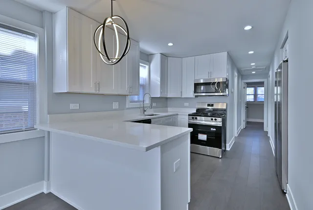 a kitchen with kitchen island granite countertop a sink stainless steel appliances and cabinets