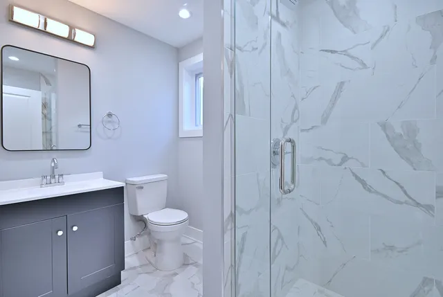 a bathroom with a granite countertop sink a toilet and a mirror