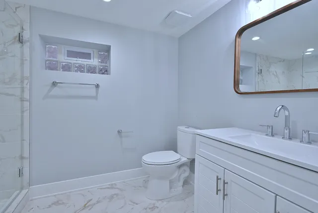 a bathroom with a granite countertop sink a toilet and a mirror