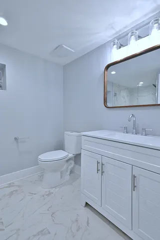 a bathroom with a toilet a sink and mirror