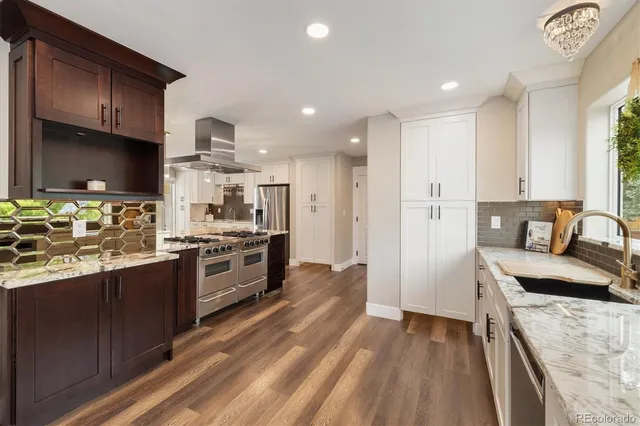 a large kitchen with stainless steel appliances granite countertop a lot of counter space and wooden floors