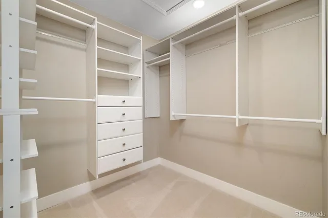 a spacious bedroom with a large bed and a chandelier fan