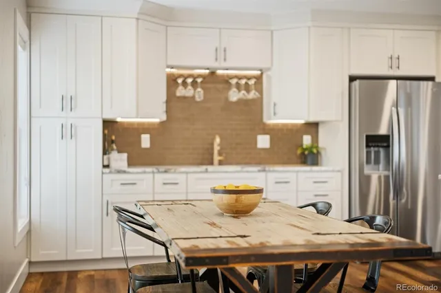 a kitchen with stainless steel appliances a white table chairs and a refrigerator