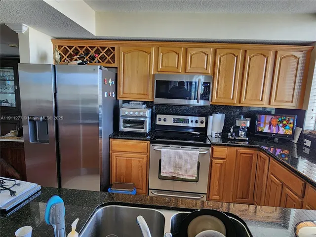 a kitchen with stainless steel appliances granite countertop a refrigerator and a stove top oven