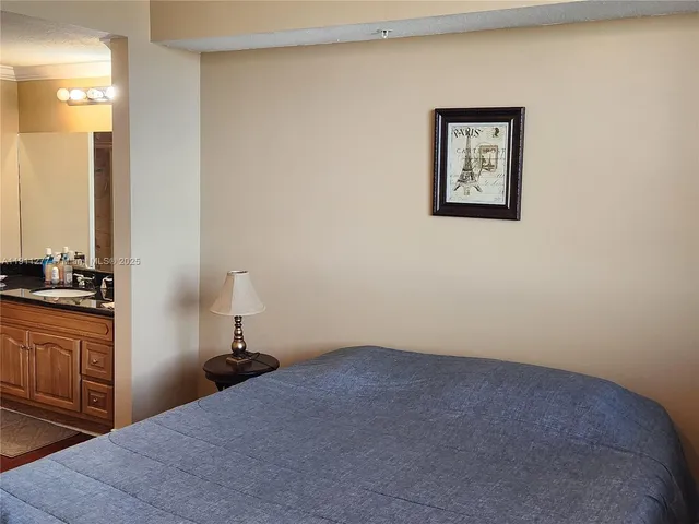 a bedroom with a bed and a lamp on dresser