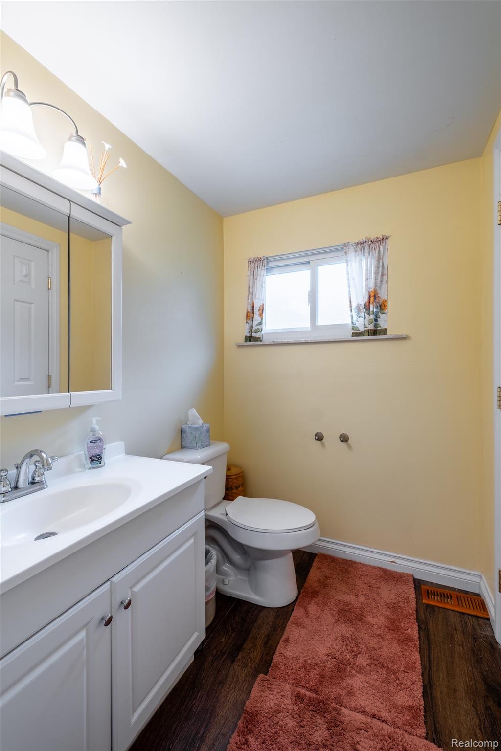 535 Snyder Road Highland, MI 48357 - Photo 12 of 23 White vanity with an integrated sink, polished chrome faucet, wood-finish flooring, and a single window