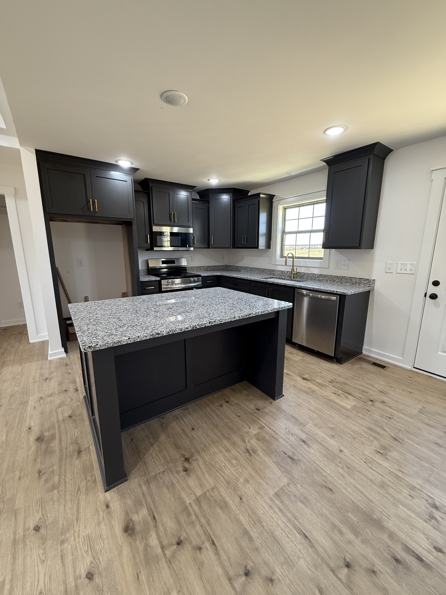 4827 Akersville Road Lafayette, TN 37083 - Photo 3 of 14 a large kitchen with kitchen island a sink dishwasher a stove and a refrigerator with wooden floor