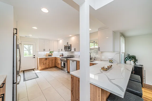 a large kitchen with kitchen island white cabinets and stainless steel appliances
