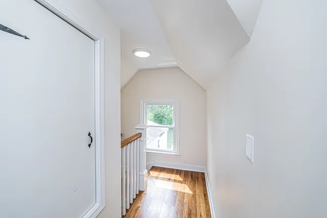 a view of a hallway with wooden floor and a living room
