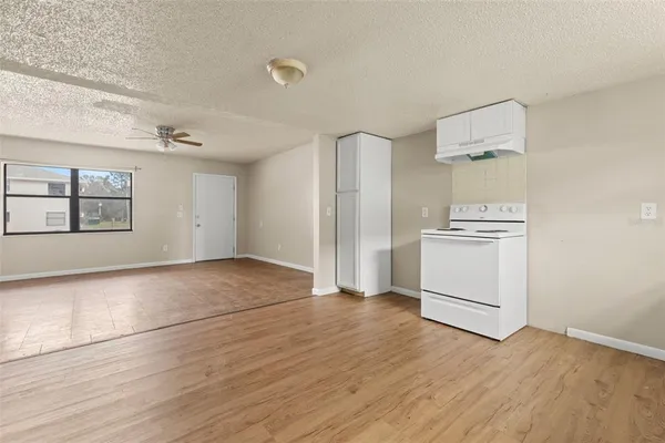an empty room with wooden floor cabinet and windows