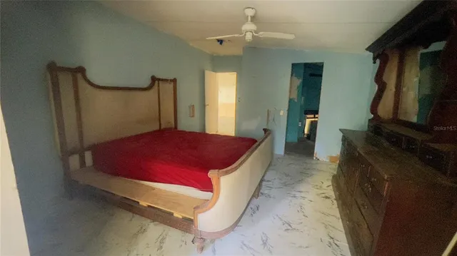 a spacious bedroom with a bed and a flat tv screen on dresser
