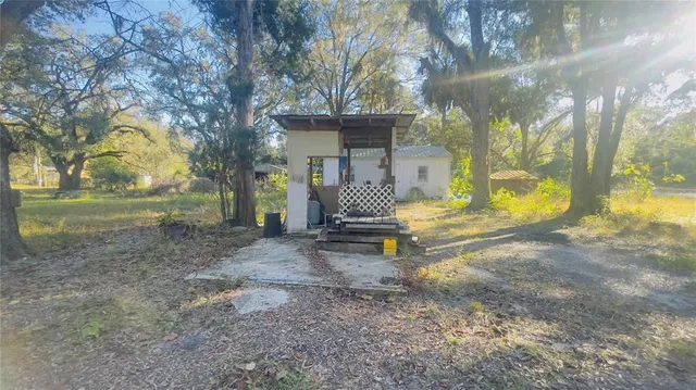 a view of a house with large trees and a small yard