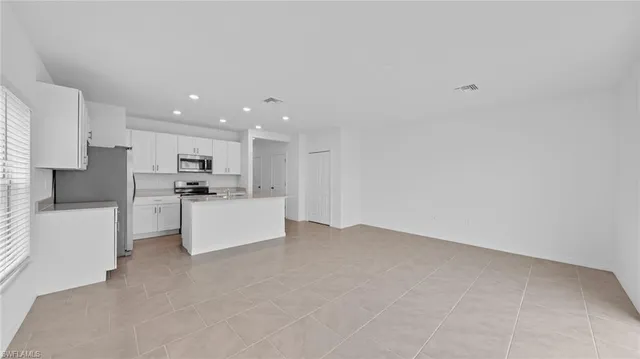 a large white kitchen with kitchen island a sink a stove a refrigerator and white cabinets