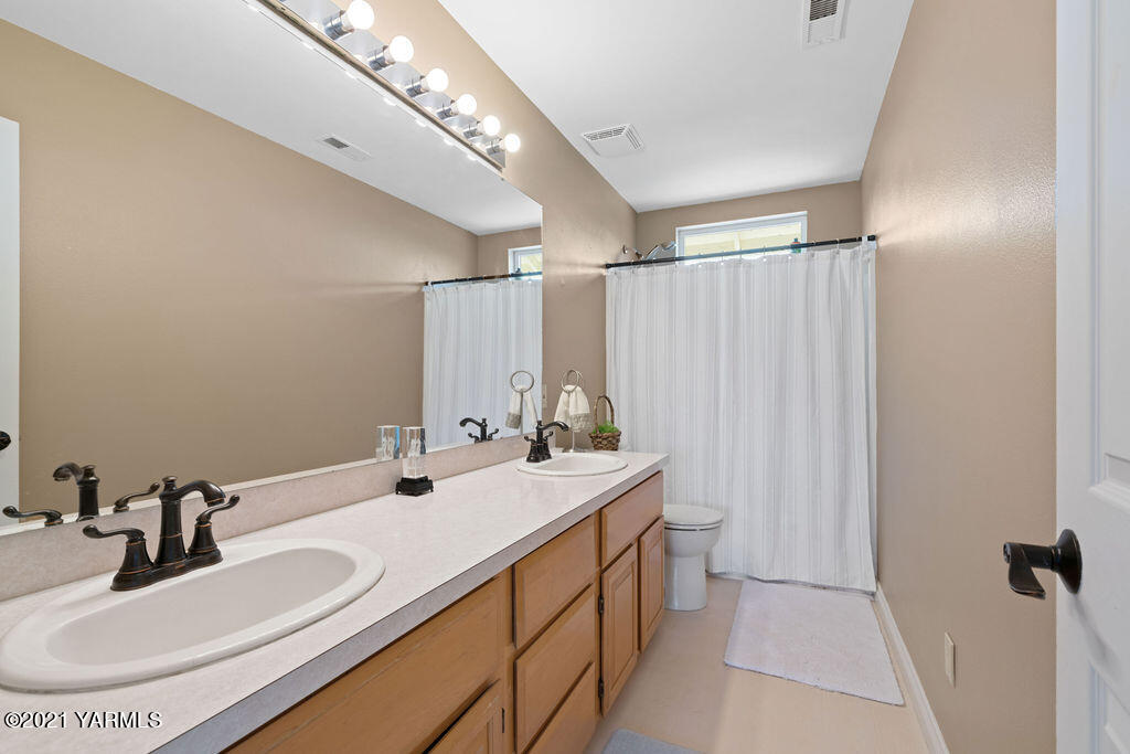 13050 West Barrett Road Yakima, WA 98908 - Photo 21 of 55 a bathroom with a double vanity sink toilet and a mirror