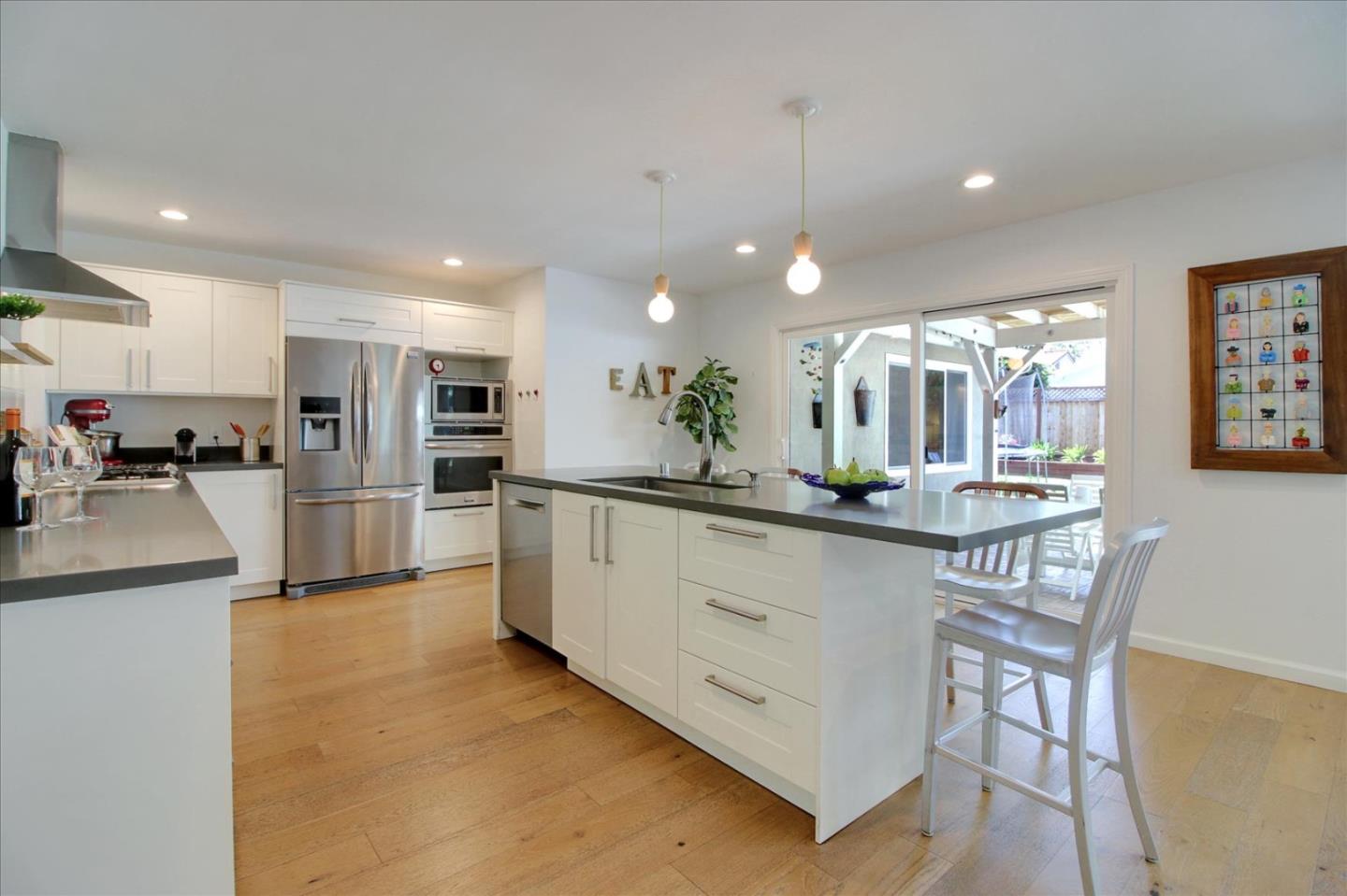 1435 Floyd Avenue Sunnyvale, CA 94087 - Photo 13 of 36 a kitchen with stainless steel appliances kitchen island granite countertop a refrigerator a stove a sink a dining table and chairs with wooden floor