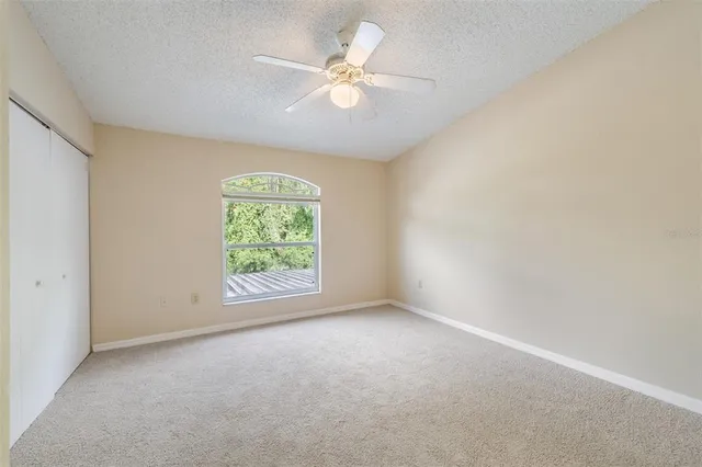 an empty room with windows and fan