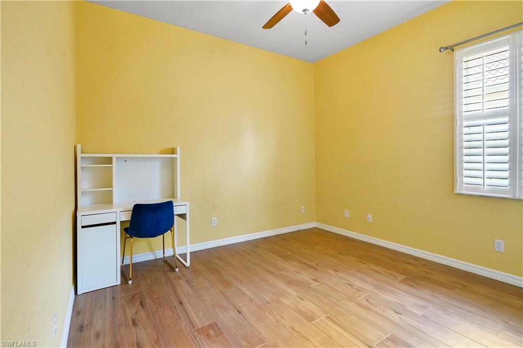 6522 Waverly Green Way Naples, FL 34110 - Photo 16 of 30 a view of an empty room with wooden floor and a window