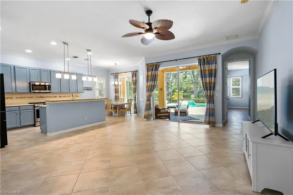 a view of a kitchen with kitchen island a large window cabinets a sink and stainless steel appliances