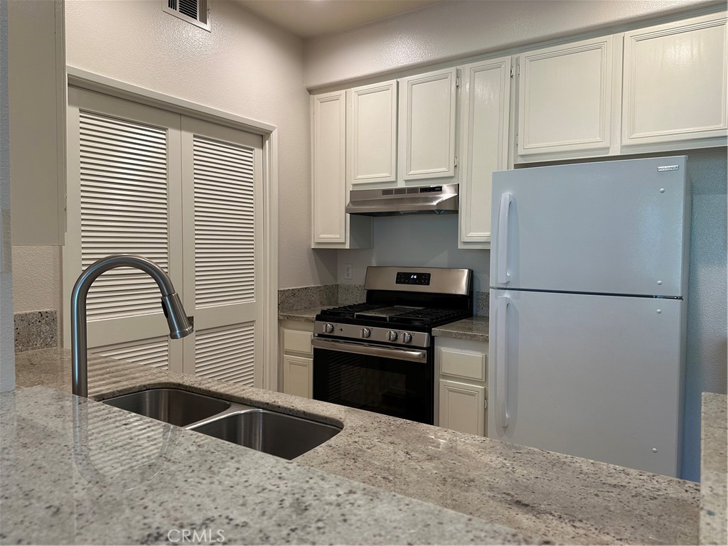 337 Chaumont Circle Lake Forest, CA 92610 - Photo 6 of 32 a kitchen with granite countertop a refrigerator a sink and white cabinets