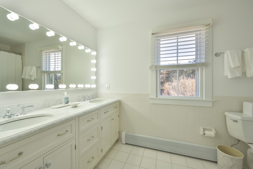 63 Monomoy Road Nantucket, MA 02554 - Photo 8 of 35 a spacious bathroom with a granite countertop toilet a sink a mirror and a window