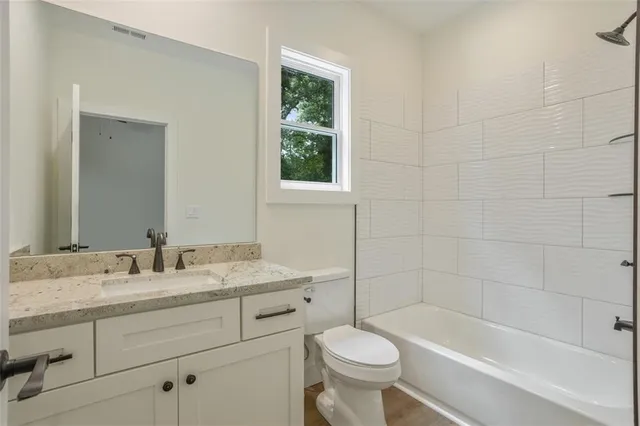 an empty room with wooden floor ceiling fan and windows
