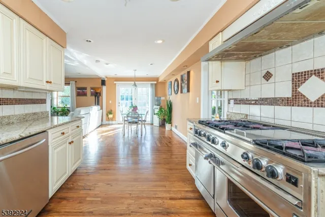 a large kitchen with stainless steel appliances granite countertop a stove and a wooden floors