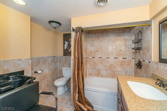 a bathroom with a granite countertop bathtub shower sink vanity and toilet