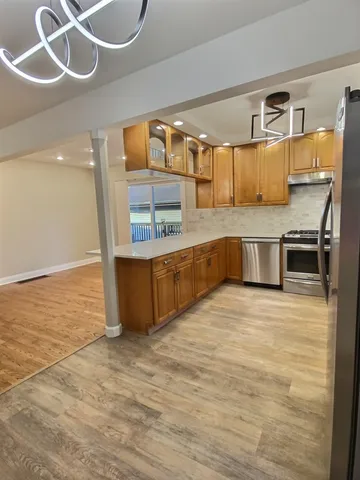 a large kitchen with stainless steel appliances granite countertop a sink and wooden cabinets