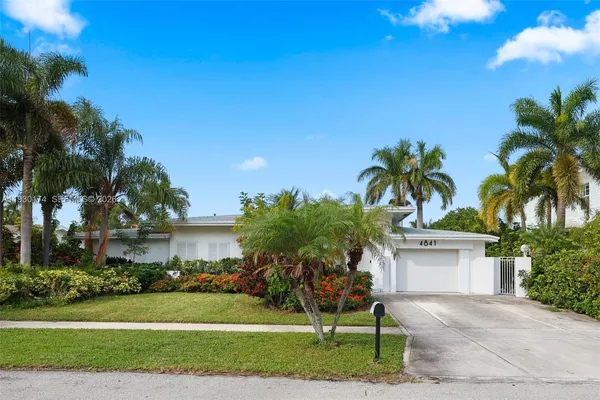 a palm tree sitting in front of a house with a big yard