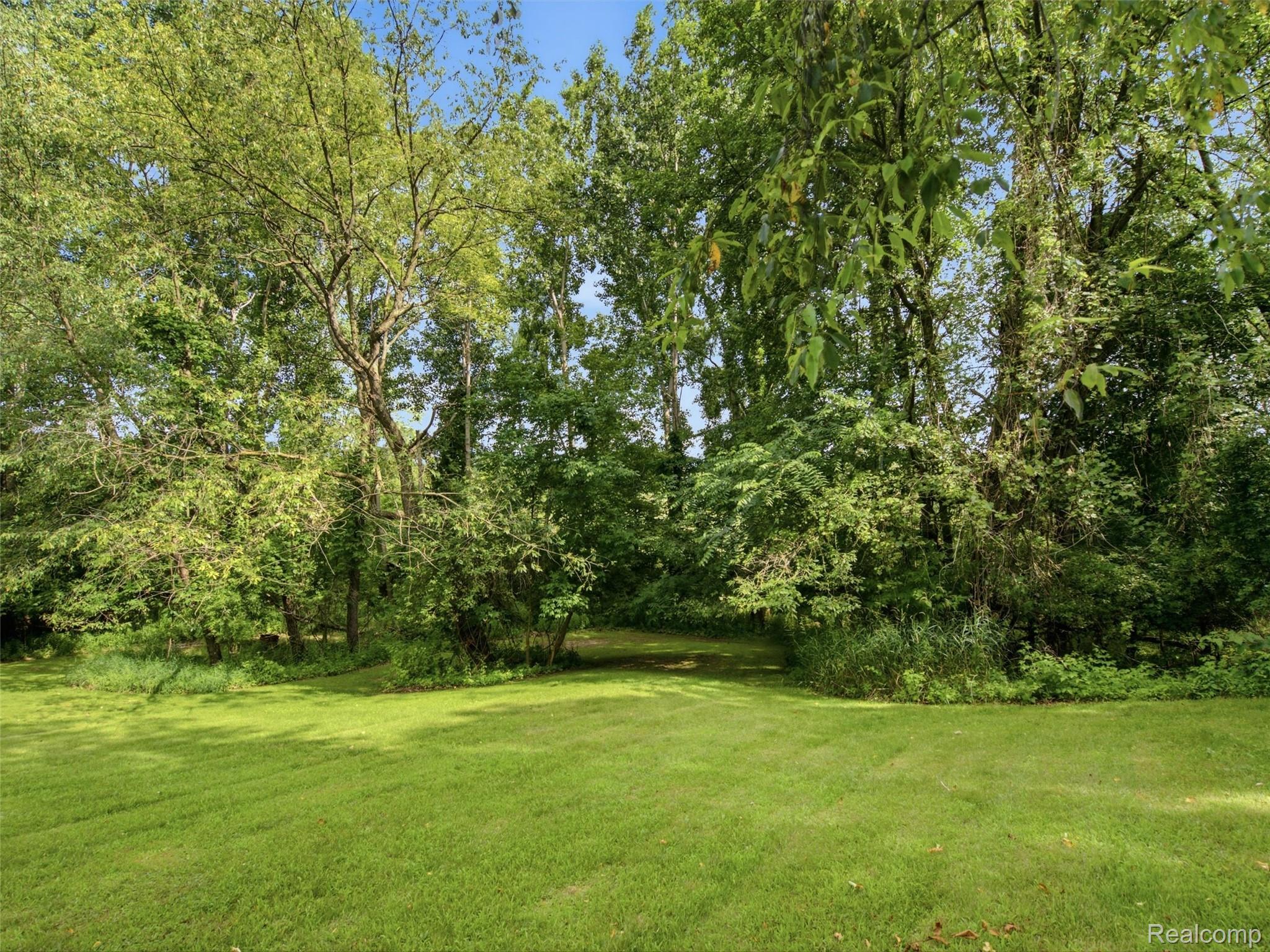 5003 Mason Road Howell, MI 48843 - Photo 36 of 59 Expansive green lawn surrounded by mature trees, offering a natural setting
