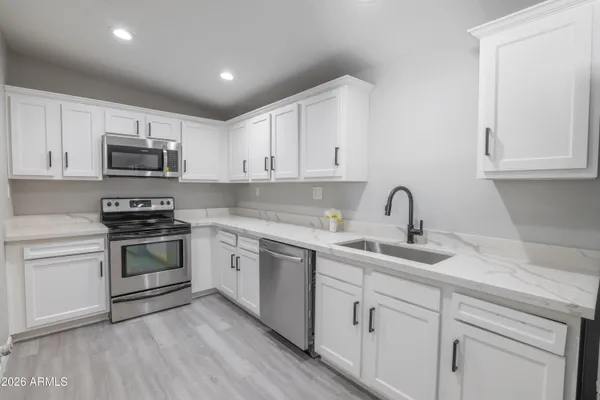 a kitchen with granite countertop white cabinets and stainless steel appliances