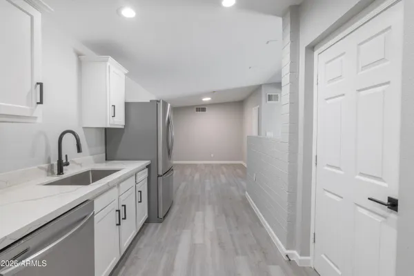 a view of a kitchen with a sink and dishwasher with wooden floor