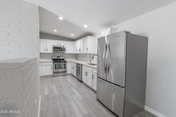 a kitchen with stainless steel appliances granite countertop a refrigerator sink and white cabinets