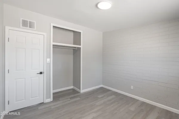 a view of an empty room with wooden floor & closet