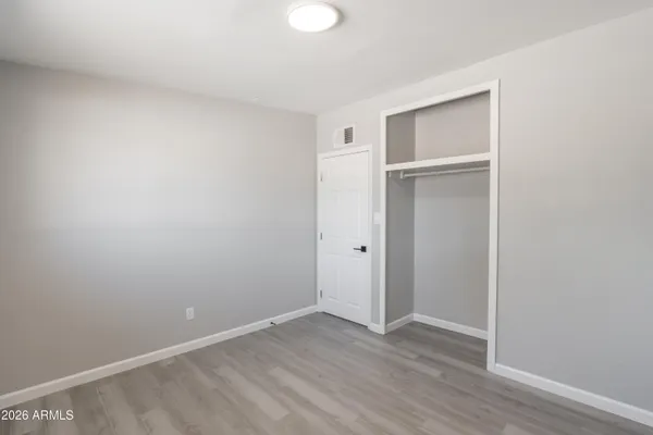 a view of an empty room with wooden floor and closet