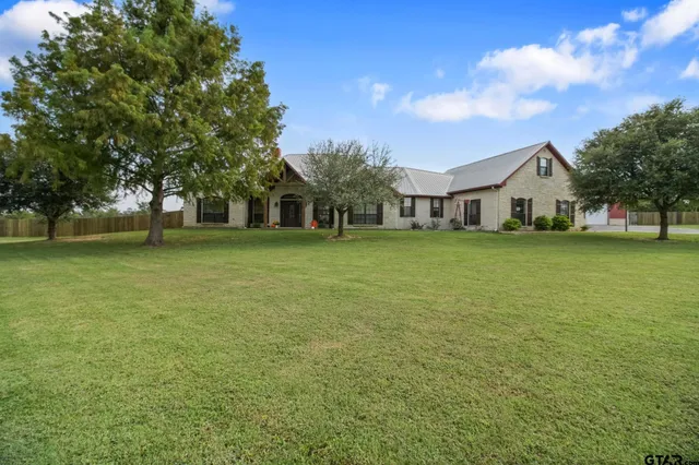 a view of a house with a big yard and large trees