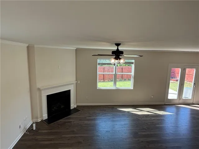an empty room with wooden floor fireplace and windows