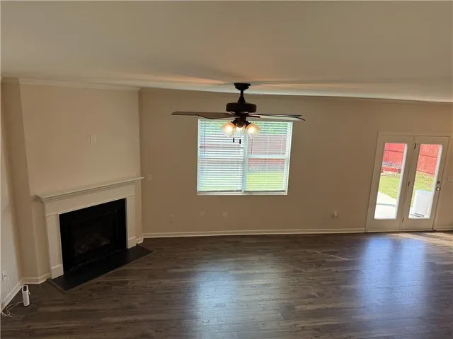 a view of an empty room with wooden floor fireplace and a window