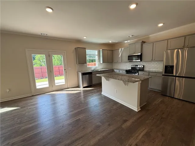 a kitchen with kitchen island granite countertop a stove a sink a refrigerator a center island and wooden floor