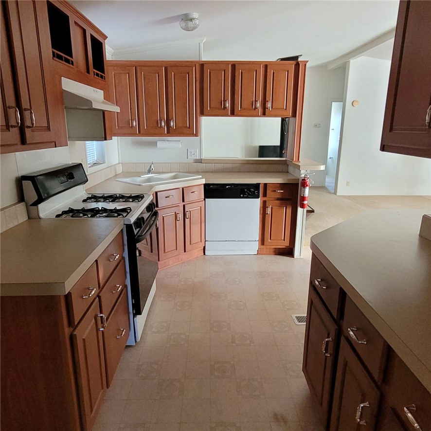9732 2nd Street Chloride, AZ 86431 - Photo 15 of 28 The kitchen features warm-toned cabinetry, a white gas range, and a white dishwasher