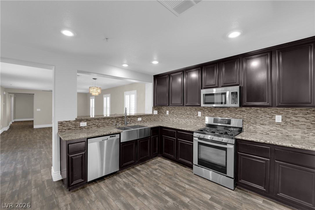 646 Monument Point Street Henderson, NV 89002 - Photo 12 of 44 A contemporary kitchen showcasing rich cabinetry, sleek stainless steel appliances, and durable flooring.