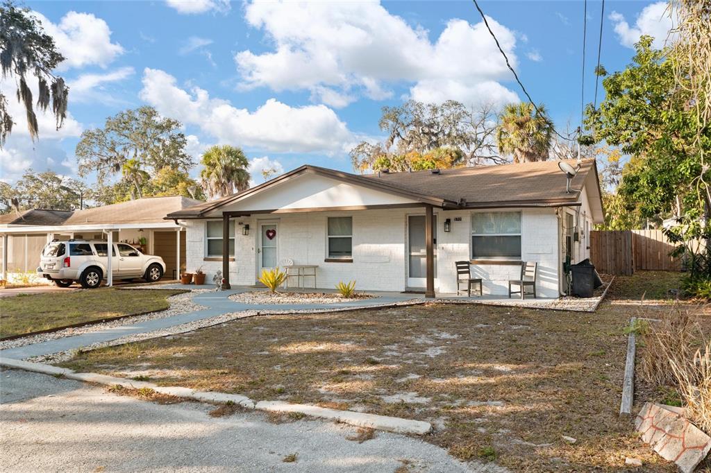 5707 Tennessee Avenue New Port Richey, FL 34652 - Photo 2 of 26 a front view of a house with a yard outdoor seating and covered with trees
