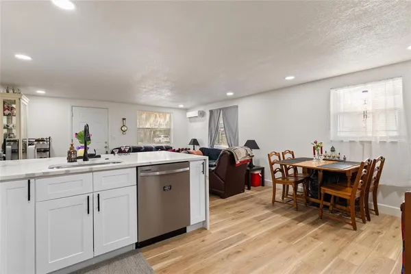 a living room with stainless steel appliances furniture a flat screen tv and a refrigerator