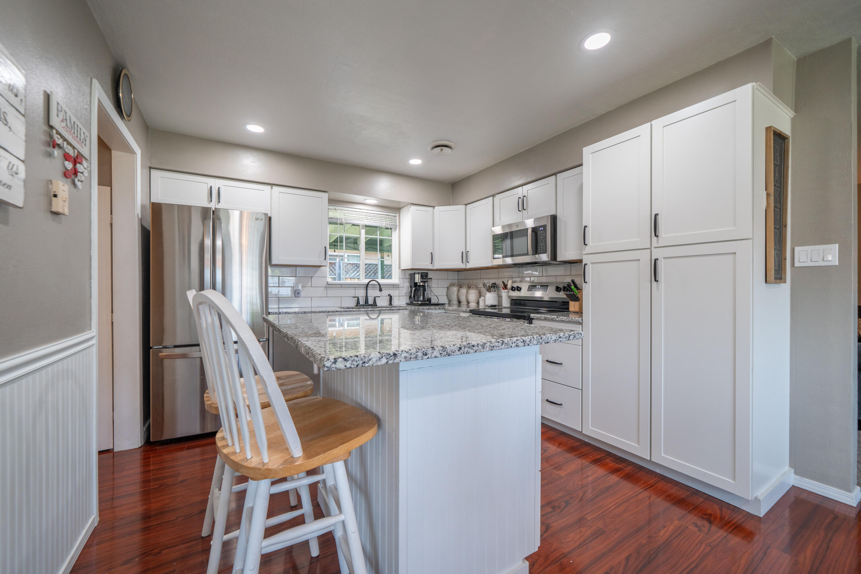 37255 Carson Street Burney, CA 96013 - Photo 14 of 40 a kitchen with stainless steel appliances granite countertop a refrigerator a microwave oven a sink dishwasher and white cabinets with wooden floor