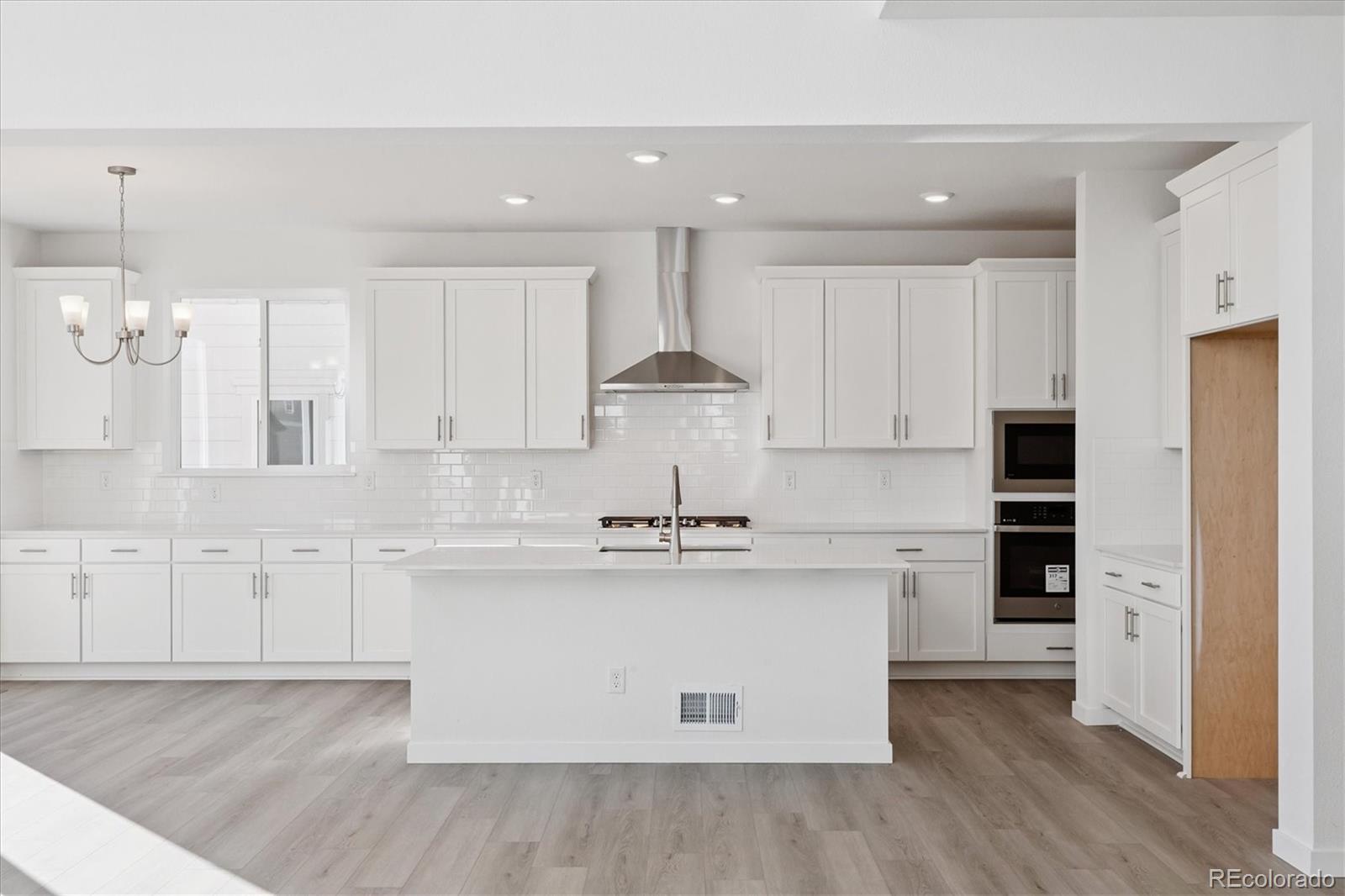 2572 West Bitterroot Place Highlands Ranch, CO 80129 - Photo 8 of 30 a kitchen with kitchen island white cabinets and stainless steel appliances