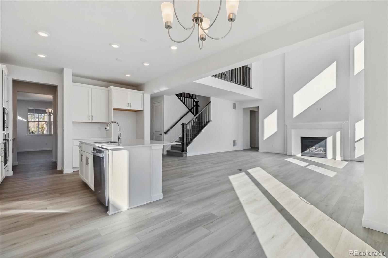 2572 West Bitterroot Place Highlands Ranch, CO 80129 - Photo 10 of 30 a kitchen with stainless steel appliances granite countertop a stove top oven a sink dishwasher a refrigerator and a fireplace with wooden floor
